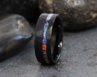 May include: A black tungsten carbide ring with a hammered finish and a thin inlay of iridescent opal. The ring is approximately 8mm wide.