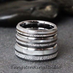 May include: Stack of four silver tungsten carbide rings with a white inlay and a brushed finish. Each ring has a different pattern of lines etched into the surface.