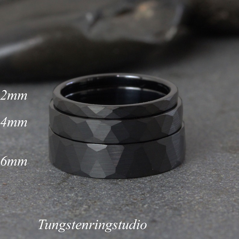 May include: Three black tungsten carbide rings stacked on top of each other. The rings are 2mm, 4mm, and 6mm wide. The rings have a hammered finish.