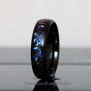 May include: A black tungsten carbide ring with a blue and silver glitter inlay. The ring is polished and has a high shine.