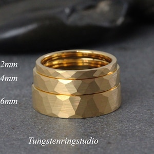 Op de afbeelding: Drie gouden ringen van wolfraamcarbide, gestapeld op elkaar. De ringen zijn 2 mm, 4 mm en 6 mm breed. De ringen hebben een gehammerde afwerking.