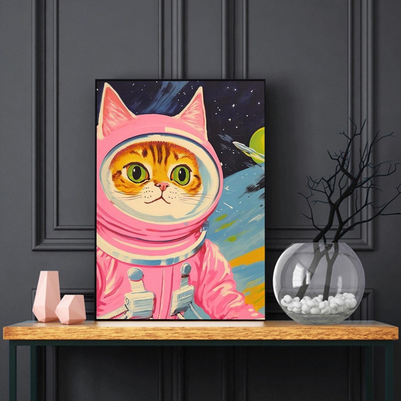 Pu&ograve; includere: Una tuta da astronauta rosa con una testa di gatto all'interno. Il gatto ha occhi verdi e un naso rosa. Lo sfondo &egrave; blu scuro con stelle e pianeti.
