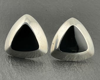 May include: A pair of silver triangle earrings with black onyx stones in the center.