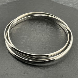May include: A silver bangle bracelet made of three interlocking rings.