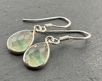 Puede incluir: Un par de pendientes de plata con piedras preciosas en forma de lágrima de color verde y azul.