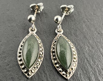 May include: A pair of silver earrings with green gemstone drops surrounded by a border of marcasite stones.