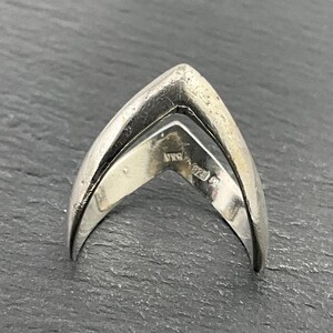Puede incluir: Anillo de plata con un diseño en forma de V. El anillo está marcado con "925 Italy".
