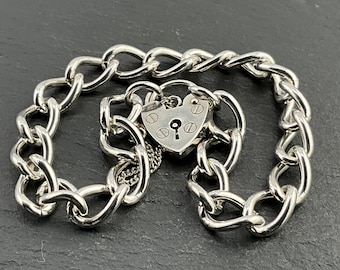 May include: A silver chain bracelet with a heart-shaped padlock charm. The chain is a curb link style and the padlock has a keyhole and a small loop at the top.
