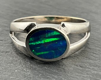 May include: A silver ring with a green and blue opal gemstone set in a bezel setting. The ring has a split shank design.
