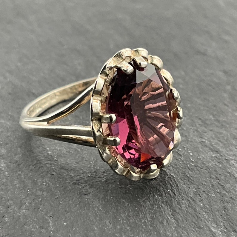 May include: A silver ring with a large, faceted, purple gemstone set in a scalloped bezel.