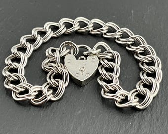 May include: A silver chain bracelet with a heart-shaped padlock charm. The chain is a curb link style and the padlock has a keyhole.