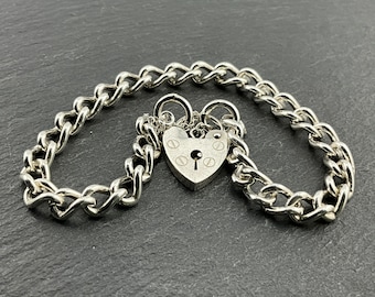 May include: A silver chain bracelet with a heart-shaped padlock charm. The chain is a curb style and the padlock has a keyhole.
