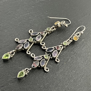 May include: Silver dangle earrings with a cluster of colorful gemstones, including amethyst, garnet, peridot, and citrine.