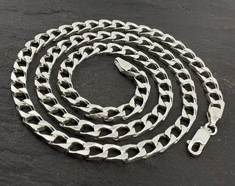 Puede incluir: Un collar de cadena curb plateado con cierre de langosta. La cadena está hecha de eslabones entrelazados que son planos y rectangulares.