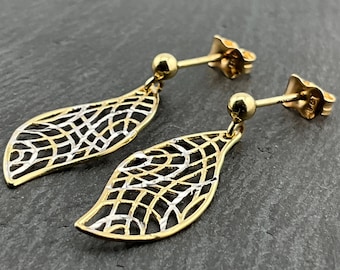 May include: A pair of gold-tone earrings with a leaf-shaped design. The earrings feature a delicate, openwork pattern with a gold and silver finish. The posts have a small ball detail. The earrings are displayed on a dark gray surface.