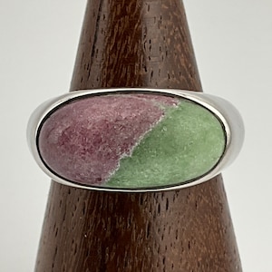 May include: A silver ring with a large oval-shaped green and pink gemstone set in the center.