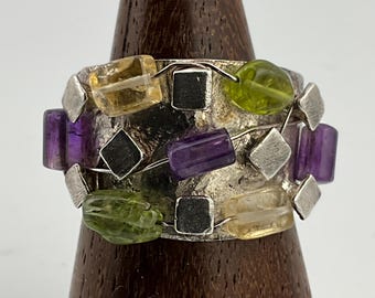 May include: A silver ring with a textured band and a variety of colorful gemstones, including amethyst, peridot, and citrine.