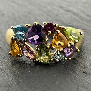 Peut inclure: Une bague en or ornée d'un groupe de pierres précieuses facettées multicolores, notamment une grande améthyste violette, une topaze bleue, une citrine jaune, un péridot vert et une tourmaline rose de formes variées.
