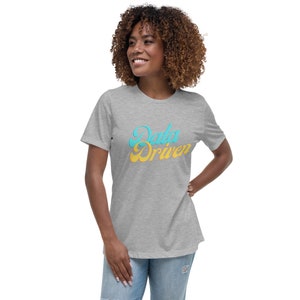 May include: A light gray t-shirt with the text "Data Driven" in a retro font. The text is in a light blue and yellow color scheme. The shirt has short sleeves and a relaxed fit.