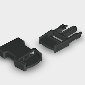 Puede incluir: Hebilla de plástico negro de dos partes, diseñada para una sujeción segura. La hebilla consta de un componente macho y otro hembra, cada uno con una forma distinta para el enclavamiento. Ideal para correas, bolsos u otras aplicaciones.