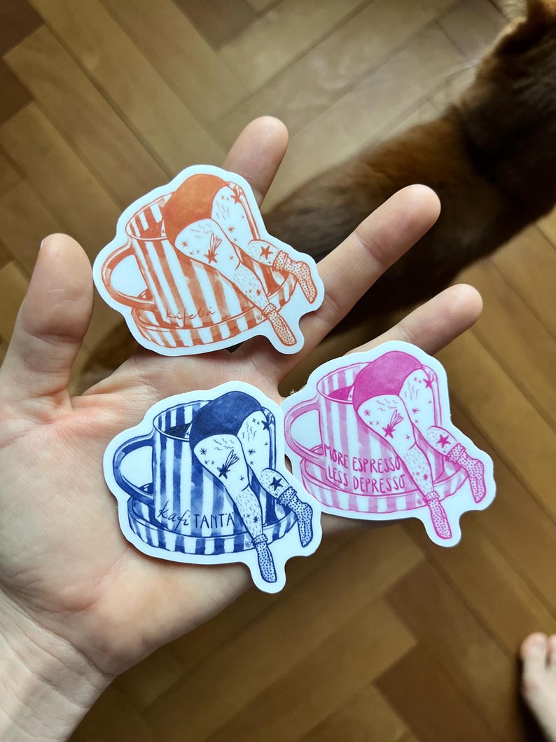 May include: Three stickers featuring illustrations of a person's legs and torso sticking out of a coffee cup. The stickers are in orange, blue, and pink, with text that reads "More Espresso Less Depresso" and "kafe tanta".
