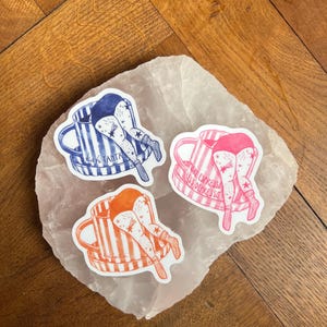 May include: Three stickers featuring a person's legs and rear end sticking out of a coffee mug. The mugs are blue and white striped, pink and white striped, and orange and white striped. The stickers have text that reads "Kaye Tanta" and "More Espresso Less Depresso".