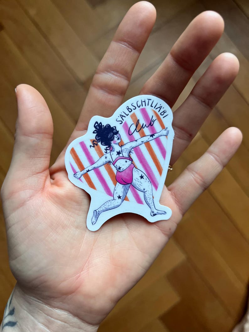 May include: A sticker with a cartoon illustration of a person in a pink swimsuit, decorated with stars, in a dynamic pose. The background has orange and white stripes, and the sticker has the text "SALBSCHTLI&Auml;BI Club".
