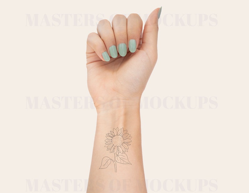 May include: A woman's wrist with a delicate line drawing tattoo of a sunflower. The tattoo is on the inside of the wrist, just below the hand. The woman is wearing light green nail polish.