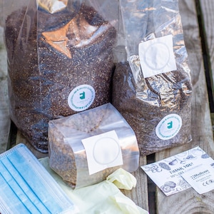 May include: A mushroom growing kit with three bags of substrate, a face mask, gloves, and a thank you card. The bags are labelled with a green logo that says "Funghi"