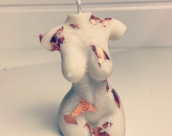 Könnte beinhalten: Weiße Kerze in Form eines Torsos mit goldenen Blattverzierungen.