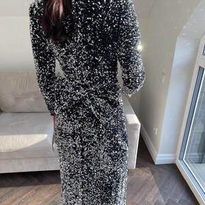 May include: A long black sequined dress with a V-neckline and long sleeves.