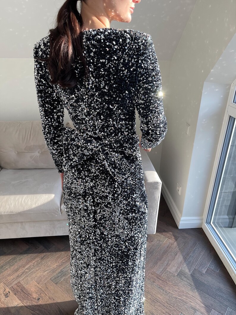 May include: A long black sequined dress with a V-neckline and long sleeves.