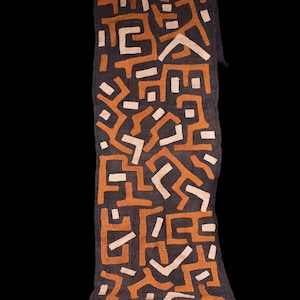 Op de afbeelding: Een rechthoekige textiel loper met een donker antracietgrijze basisstof. Het oppervlak is versierd met een ingewikkeld, herhalend patroon van abstracte geometrische vormen en lijnen in contrasterende tinten roestoranje en gebroken wit.