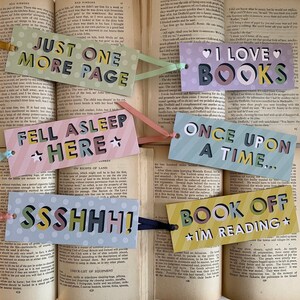 May include: A collection of six decorative bookmarks, each with a different phrase, such as "Fell Asleep Here" and "Book Off." Each bookmark has a ribbon attached. Ideal for reading.