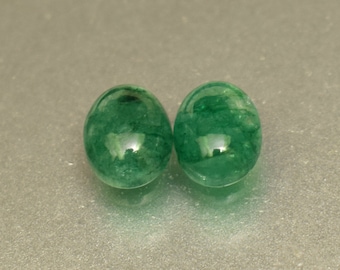 Pode incluir: Duas pedras preciosas redondas de esmeralda verde. As pedras preciosas são lisas e polidas.