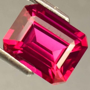 Peut inclure: Une pierre précieuse de couleur rose vif taillée en émeraude avec un haut poli.