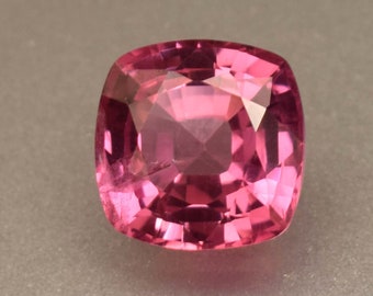 Può includere: Una pietra preziosa rosa con taglio a cuscino quadrato. La pietra è sfaccettata e ha un alto livello di brillantezza.