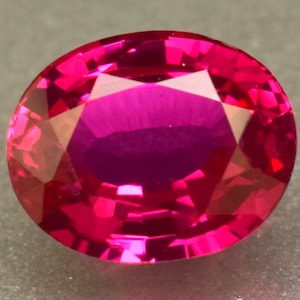 May include: A vibrant pink oval-shaped gemstone with a faceted cut.