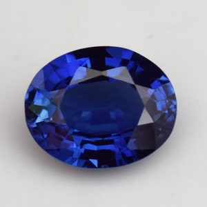Puede incluir: Una piedra preciosa de zafiro ovalada azul oscuro con un corte facetado.