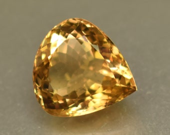 May include: A golden yellow gemstone with a teardrop shape and faceted cut.
