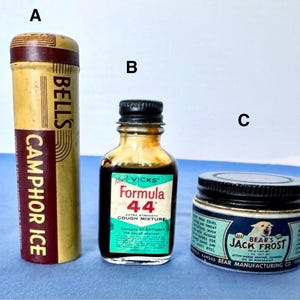 May include: Three vintage medicinal products: a cylindrical container of Bell's Camphor Ice, a small bottle of Vicks Formula 44 cough mixture, and a jar of Bear's Jack Frost ointment. The labels are visible on each container.