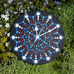 May include: A black clock with white hands and a mandala design painted in blue, red, and white dots.