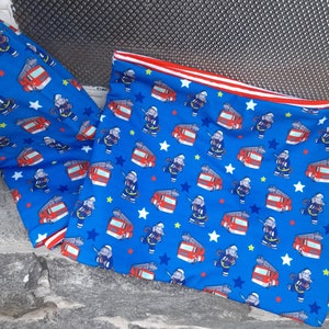 Könnte beinhalten: Blauer Stoff mit einem sich wiederholenden Muster aus roten Feuerwehrautos und grauen Elefanten auf blauem Hintergrund mit weißen Sternen. Der Stoff hat einen roten und weißen Saum.