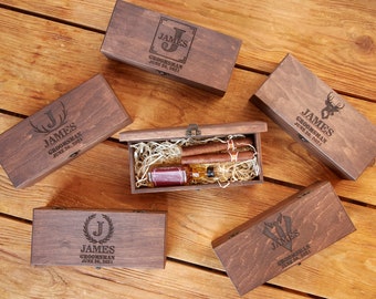 May include: Five wooden boxes with engraved text. Each box has a different design, including a monogram, a deer, and a bow tie. The boxes are all closed and are arranged on a wooden surface.