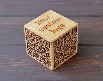May include: A wooden cube with a QR code and the text "Your custom logo" engraved on it.