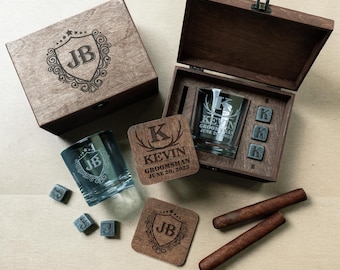 Puede incluir: Un juego de regalo de madera con un vaso de whisky personalizado, posavasos y cubitos de hielo. El vaso y los posavasos están grabados con iniciales y nombres. El juego incluye dos puros y se presenta en una caja de madera.