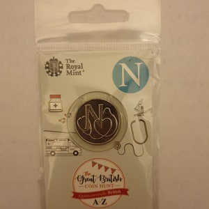 Op de afbeelding: Een ongebruikte 10p munt uit 2018 uit het VK in een transparante plastic verpakking. De munt toont de letter 'N' met een stethoscoop ontwerp. De verpakking bevat het Royal Mint logo en de merknaam 'The Great British Coin Hunt'.
