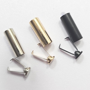 May include: Three metal tube-shaped clasps in silver, gold, and black. Each clasp has a spring-loaded mechanism with a small, round base. The clasps are designed to secure items.