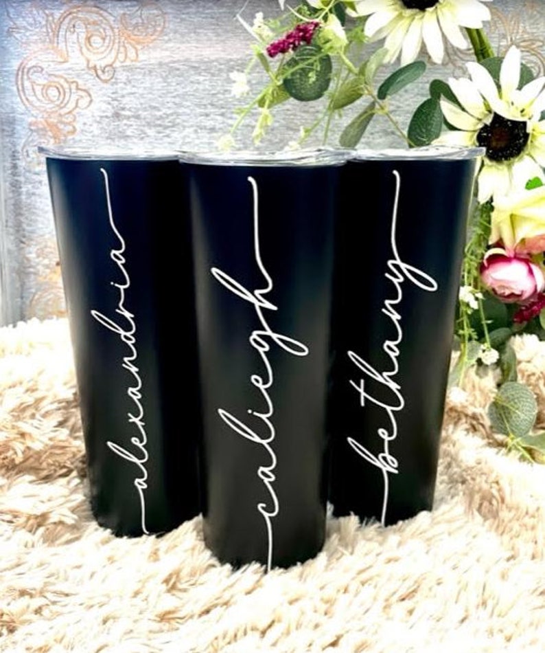 May include: Three black stainless steel tumblers with white personalised names:  "Alexandria", "Calliegh", and "Bethany".
