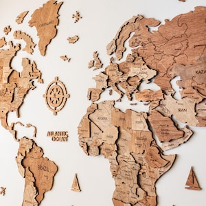 Pode incluir: Um mapa-m&uacute;ndi de madeira com contornos detalhados de pa&iacute;ses, incluindo EUA, Brasil e Gronel&acirc;ndia. O mapa apresenta r&oacute;tulos oce&acirc;nicos como "Oceano Atl&acirc;ntico" e "Oceano &Aacute;rtico". Velas decorativas de madeira e uma rosa dos ventos tamb&eacute;m est&atilde;o inclu&iacute;das.
